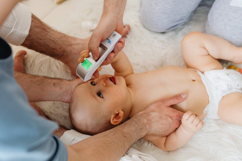 Father uses a digital thermometer to measure his baby's temperature at home.